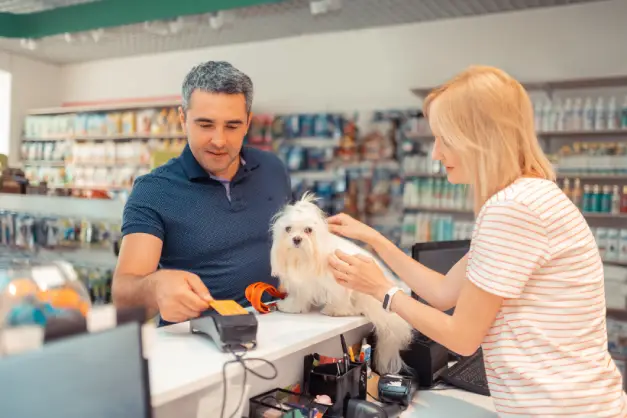 Hombre pagando en una petshop con su canino sobre el mostrador